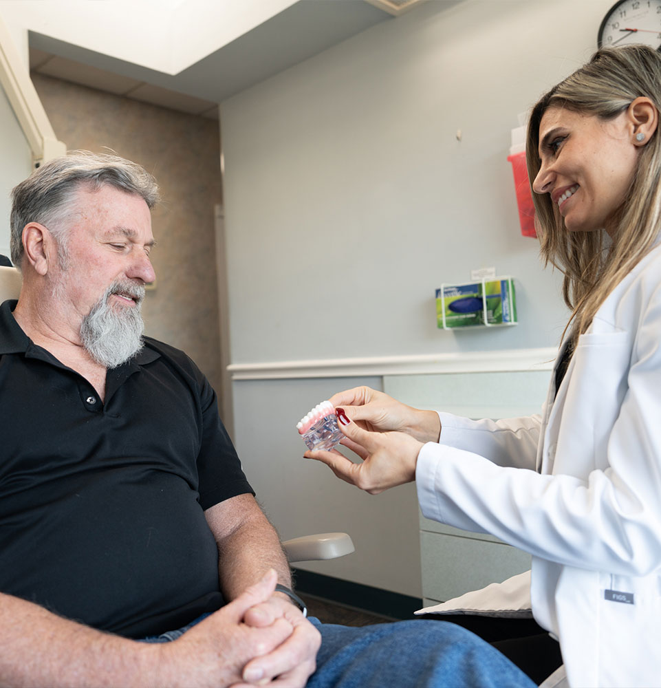 patient smiling while doctor looking over dental model