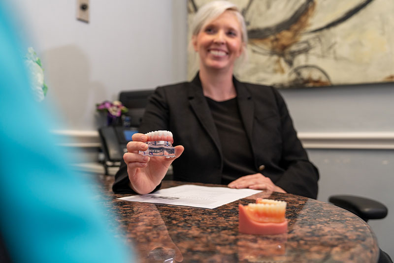 staff member going over dental implant model with patient within the dental center
