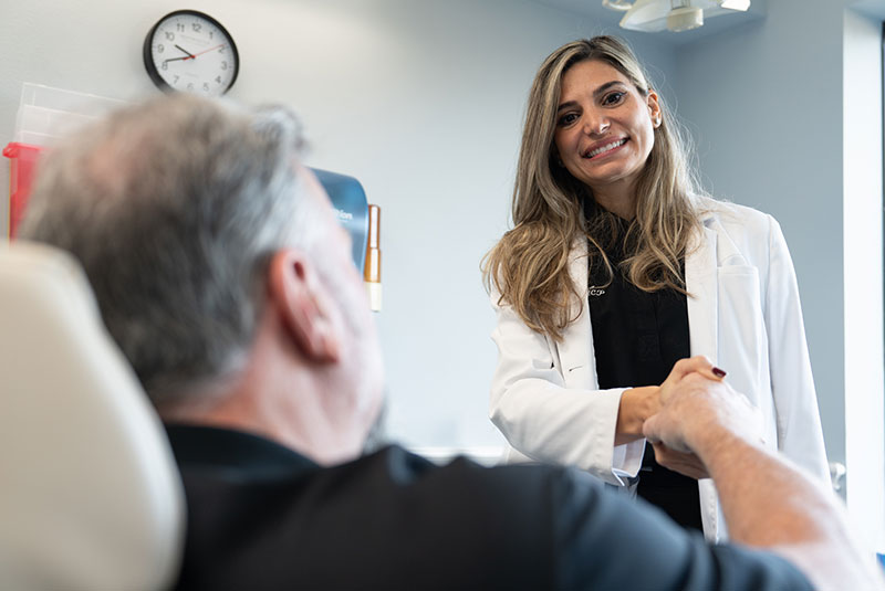doctor and patient shaking hands within the dental center after procedure